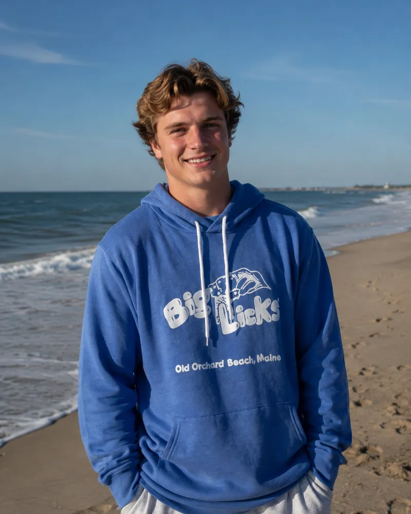 A man wearing the royal blue Big Licks hooded sweatshirt on the beach
