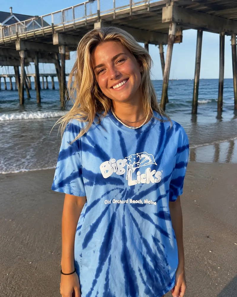 A woman wearing the blue tie-dye Big Licks t-shirt by the pier